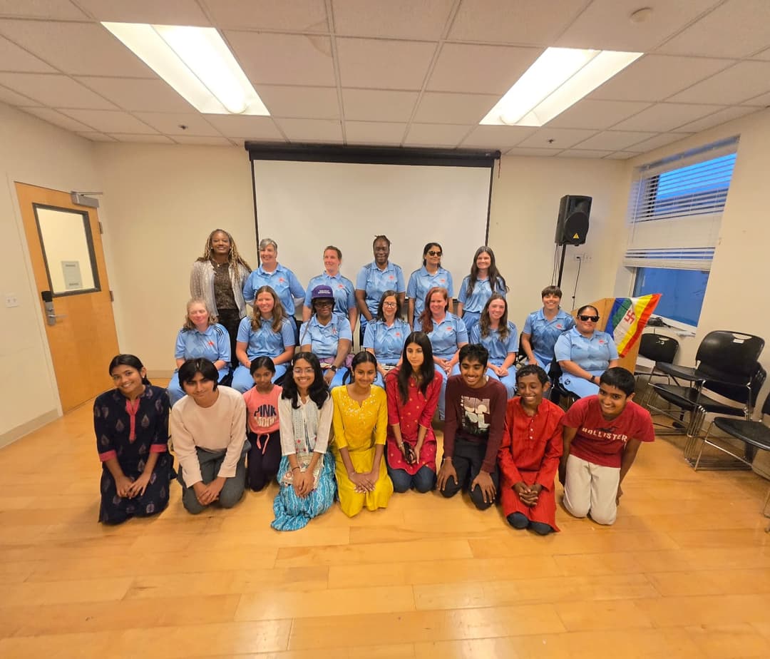 Cricket team clicking a picture with young girls and boys.