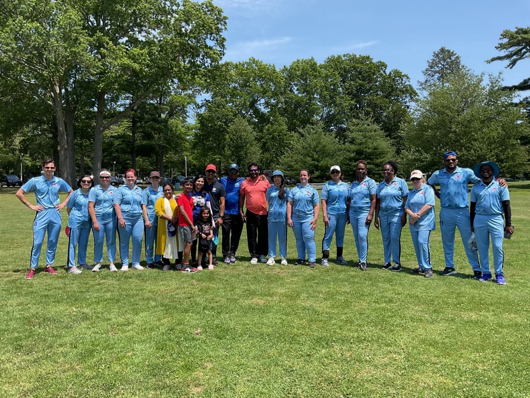 A bowler in the action to bowl, the ball has left her hand. The non striker, couple of fielders and the umpire are also visible in the shot. 