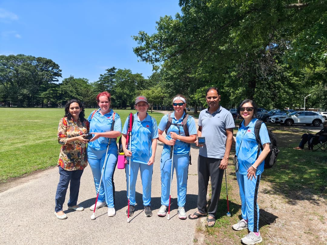A bowler in the action to bowl, the ball has left her hand. The non striker, couple of fielders and the umpire are also visible in the shot. 