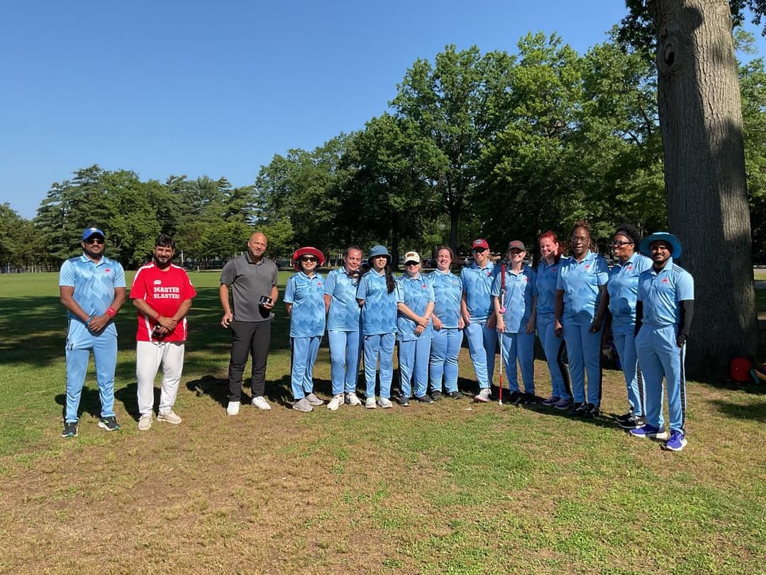 A bowler in the action to bowl, the ball has left her hand. The non striker, couple of fielders and the umpire are also visible in the shot. 