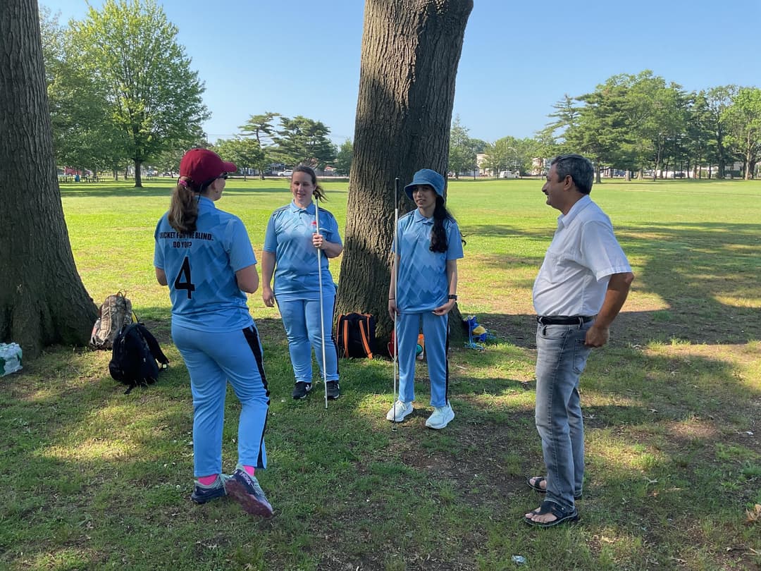 A bowler in the action to bowl, the ball has left her hand. The non striker, couple of fielders and the umpire are also visible in the shot. 