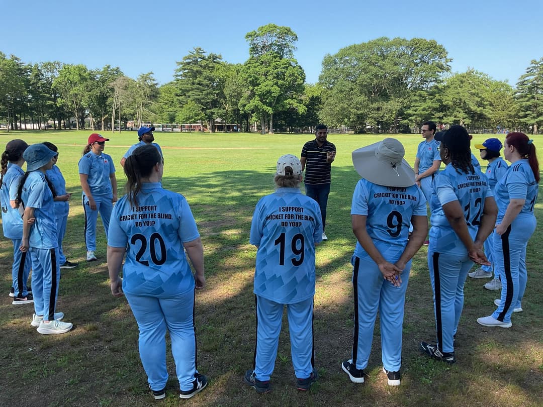 A bowler in the action to bowl, the ball has left her hand. The non striker, couple of fielders and the umpire are also visible in the shot. 